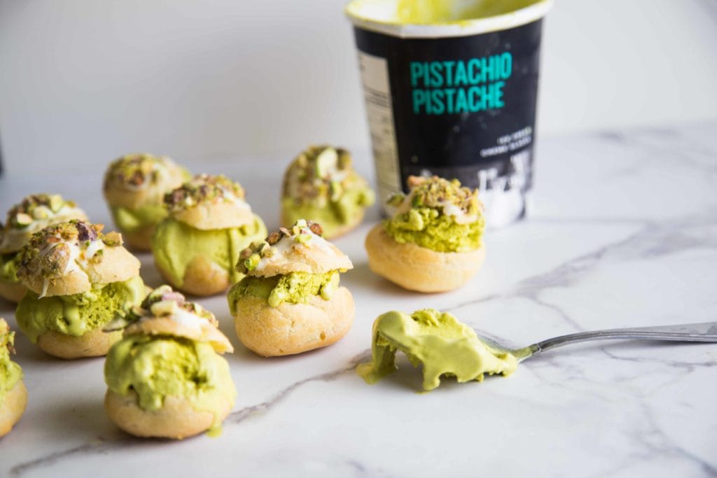 Profiteroles à la pistache avec garniture au chocolat blanc, pistaches concassées et fleur de sel / Cinq Fourchettes